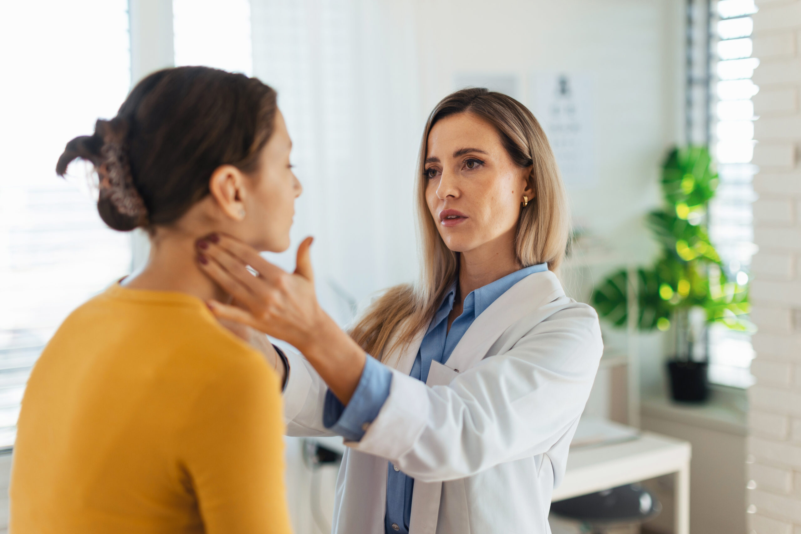 Doctor examining lymph nodes on neck of the woman.