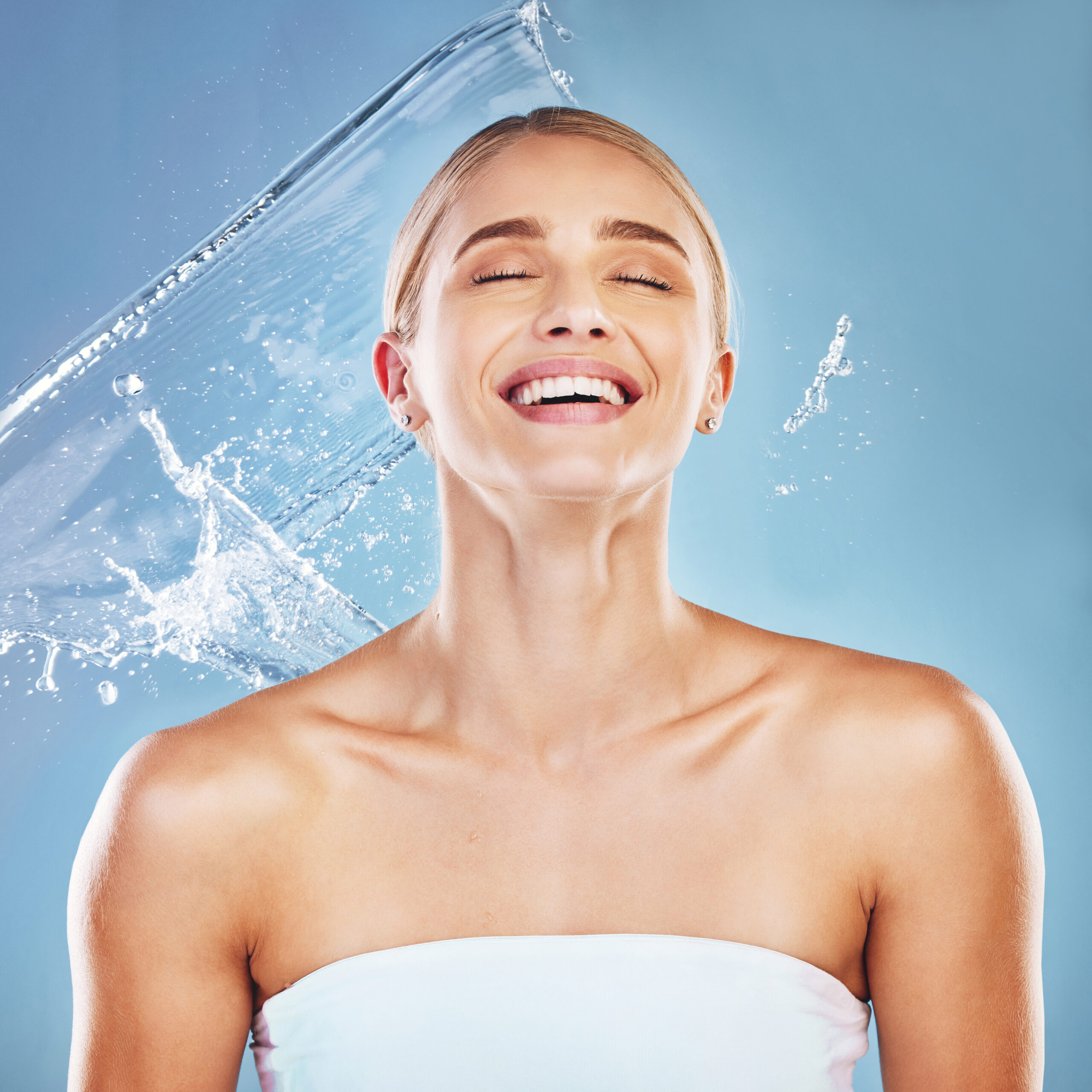 Water, beauty and cleaning with a model woman in studio on a blue background for hydration in a splash